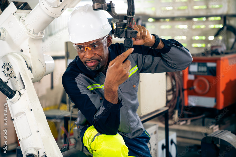 African American factory worker working with adept robotic arm in a workshop . Industry robot progra