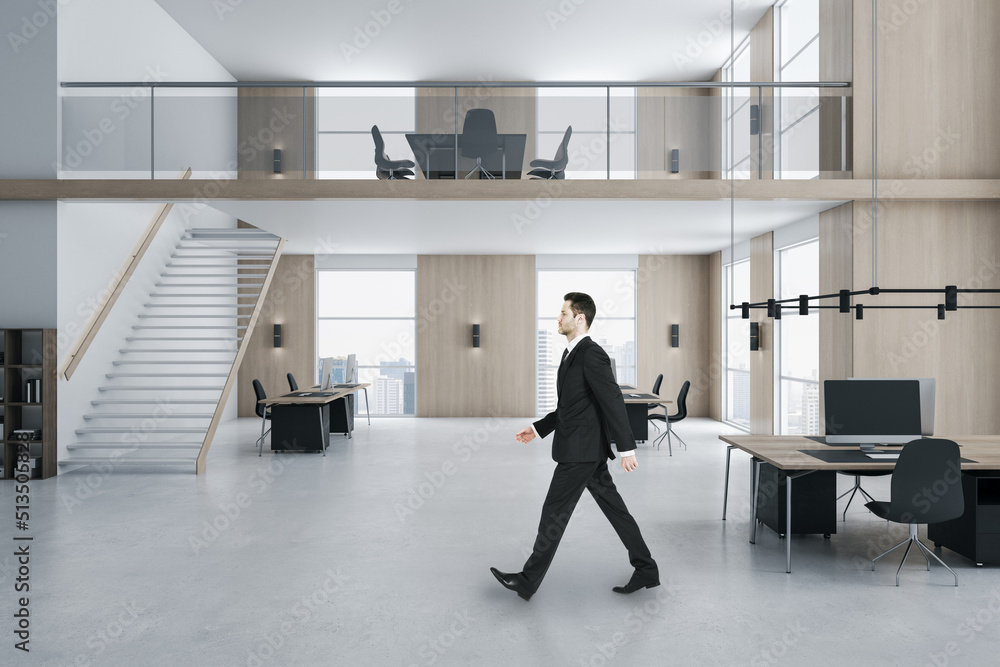 Young businessman walking in modern two floors wooden and concrete duplex office interior with panor