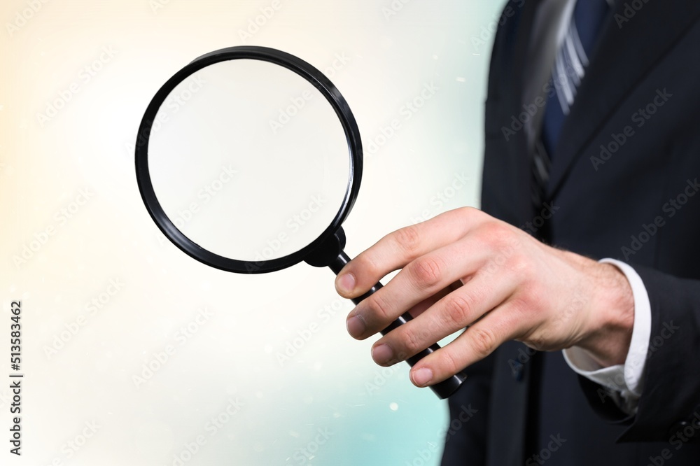 Hand holding magnifying glass on the background. Information search, data analysis and verification 