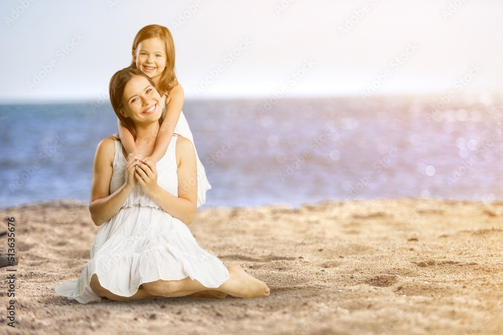 Young woman with her little cute girl on beach during sunset. Cheerful and cute daughter walking and