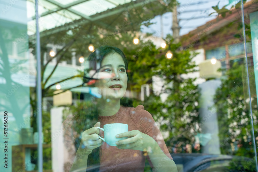 Beautiful girl drinking coffee at table in cafe near the window.