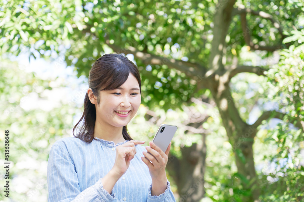 屋外での笑顔でスマホを使う女性