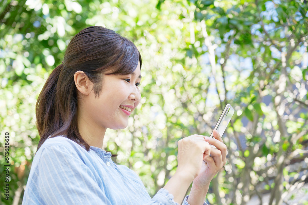 屋外での笑顔でスマホを使う女性