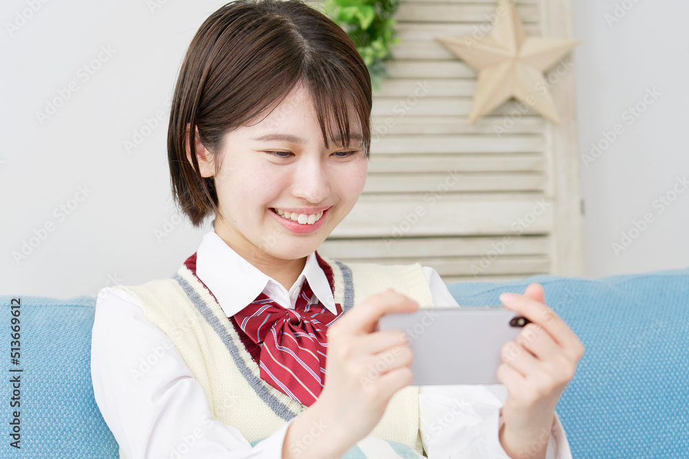 自宅でスマホを見る女子高生