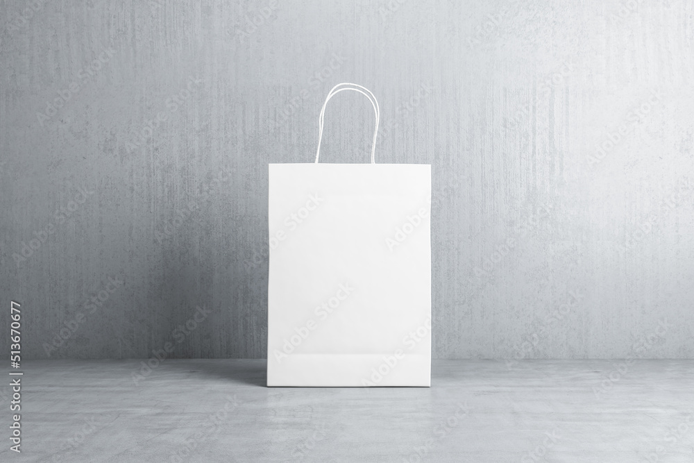 Front view on blank white paper shopping bag with space for your logo or text on concrete floor on g