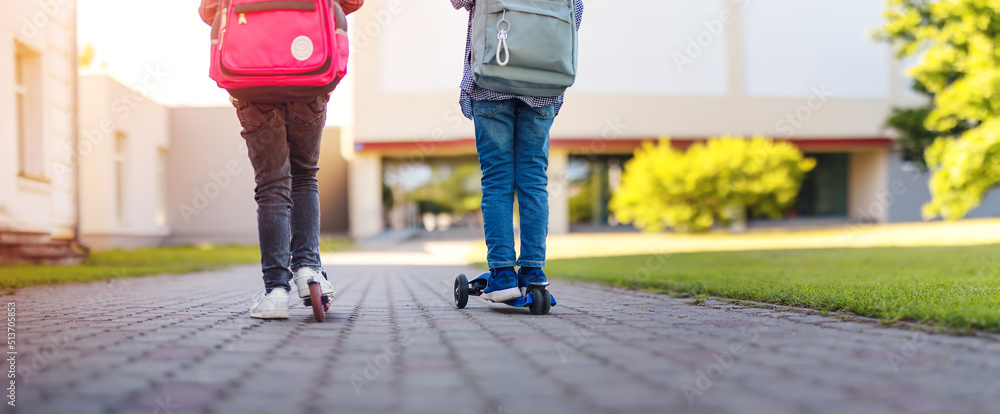 女孩和男孩在学校里骑着滑板车学习。