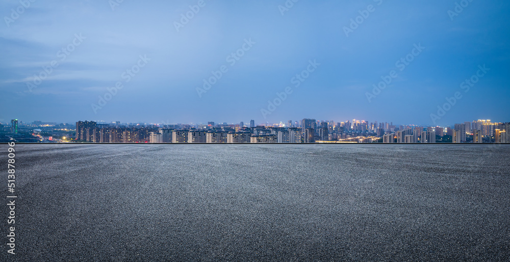 沥青路和现代城市天际线，夜晚有建筑景观。高角度视野。