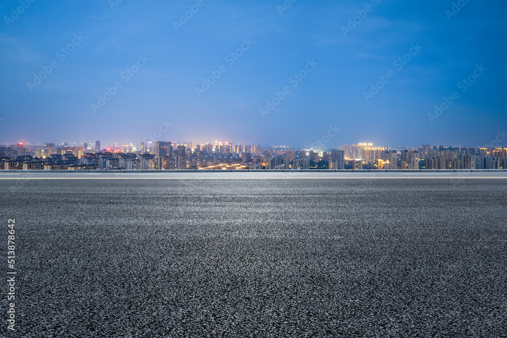 沥青路和现代城市天际线，夜晚有建筑景观。高角度视野。