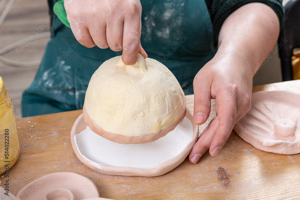 Close up of female potter hands holding clay cup handcraft crockery in studio.