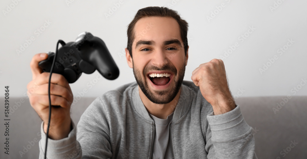 Happy young man playing video games at home