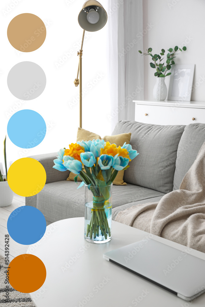 Vase with bouquet of beautiful tulips and laptop on table in living room