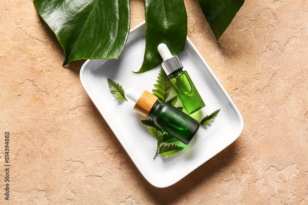 Bowl with bottles of natural serum on color background