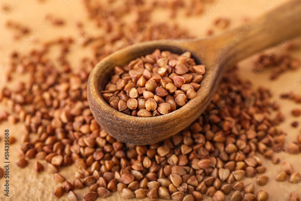 Wooden spoon and scattered buckwheat grains on table, closeup