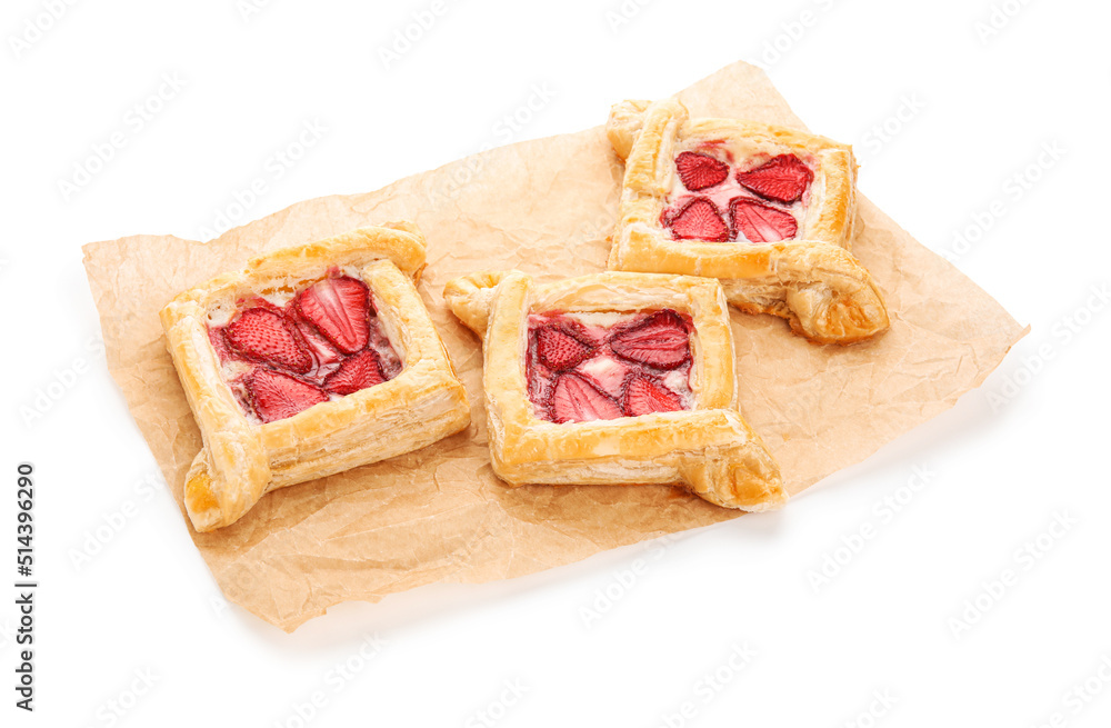 Parchment paper with strawberry puff pastries on white background