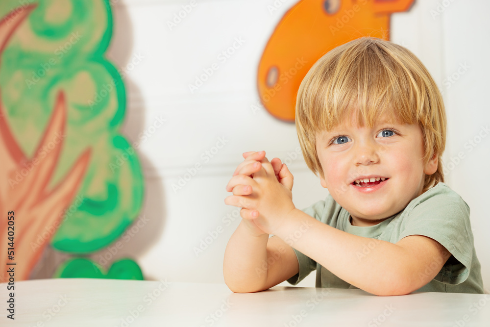 幼儿园教室里，男孩手牵着手坐在桌子旁