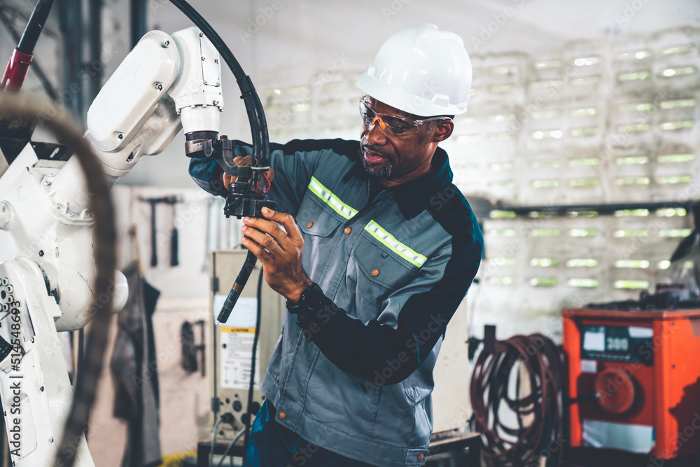 African American factory worker working with adept robotic arm in a workshop . Industry robot progra