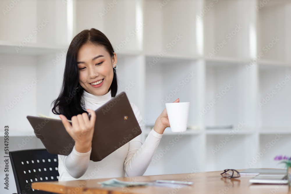 Attractive beautiful Asian woman reading a book in the home office.