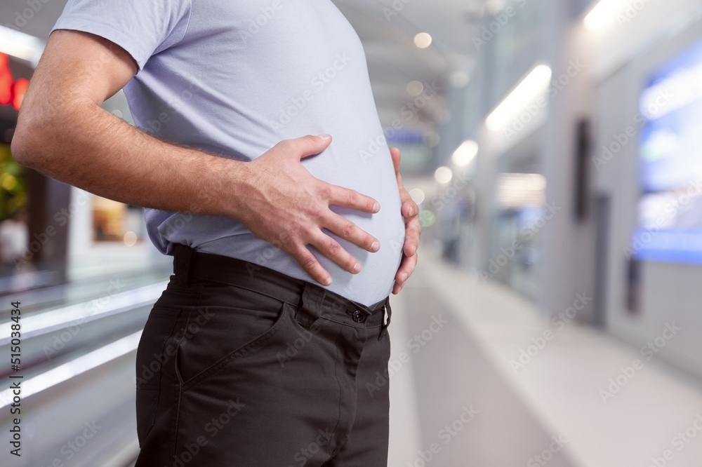 Cropped of overweight fat man holding tummy flabs with obesity. Inclination body. Adipose stomach. B