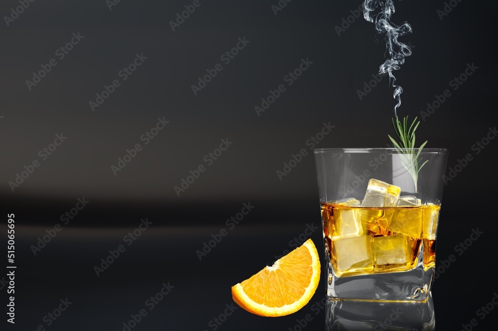 Whiskey or cognac in cristal glass with smoked rosemary, and slice of orange. Alcoholic drink.