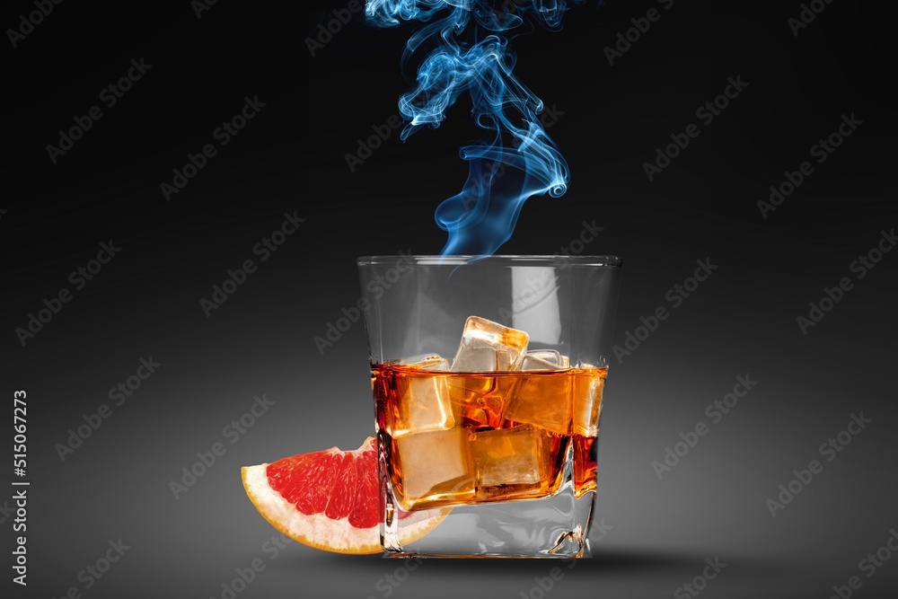 Whiskey or cognac in cristal glass with smoked rosemary, and slice of orange. Alcoholic drink.