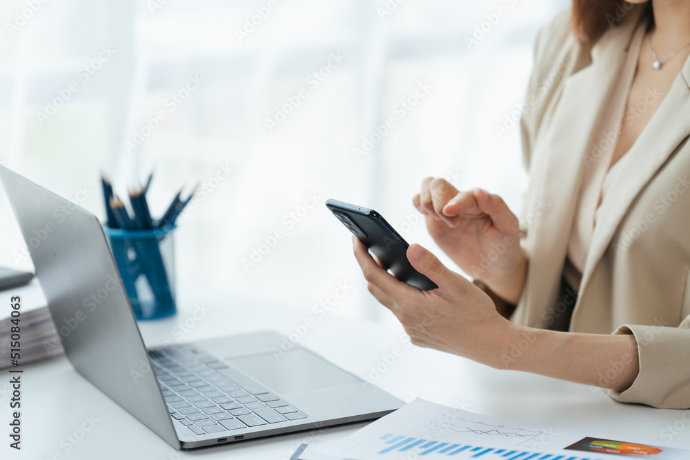 Asian businesswoman in formal suit in office happy and cheerful during using smartphone and working.