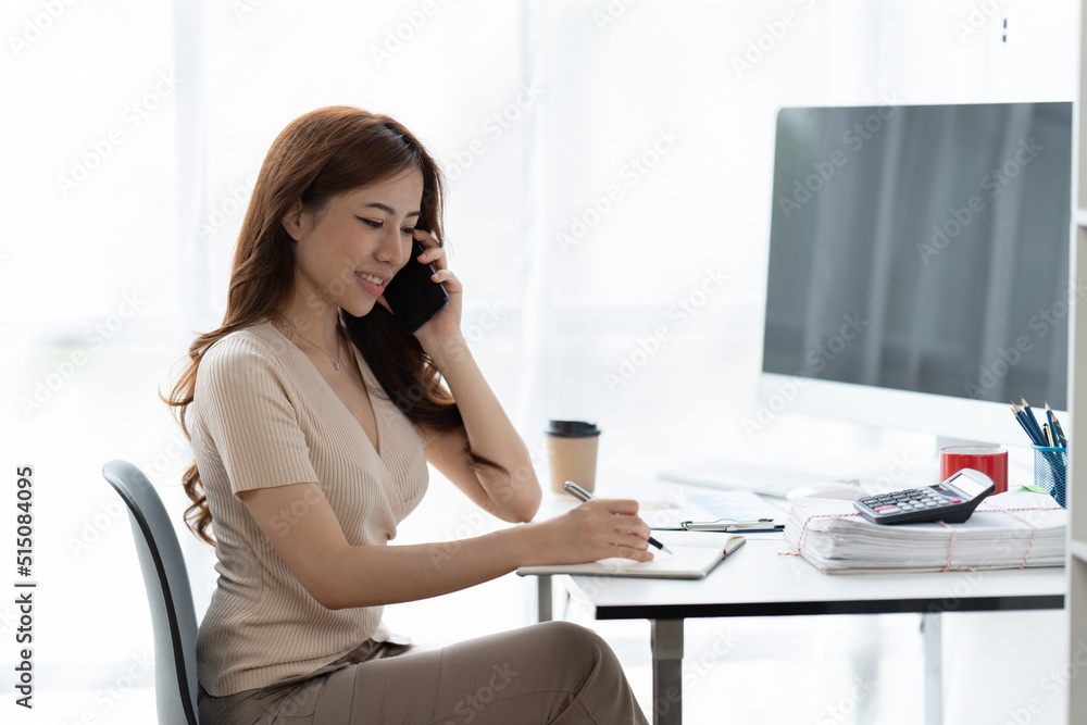 Asian businesswoman in formal suit in office happy and cheerful during using smartphone and working.