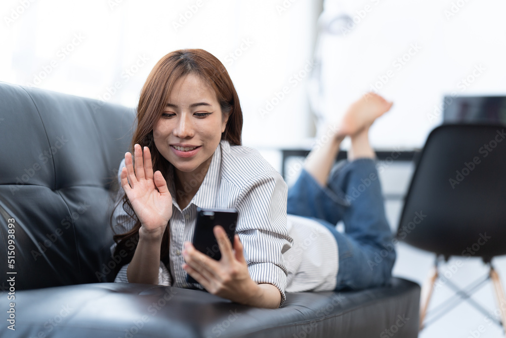 Happy young woman using smartphone at home sitting on soft couch, she is using a smartphone and text