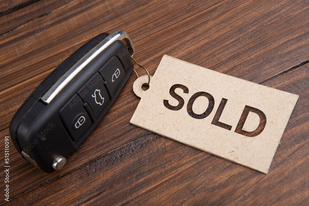 Car auction Sold out concept. Vehicle security key with tag on the wooden background