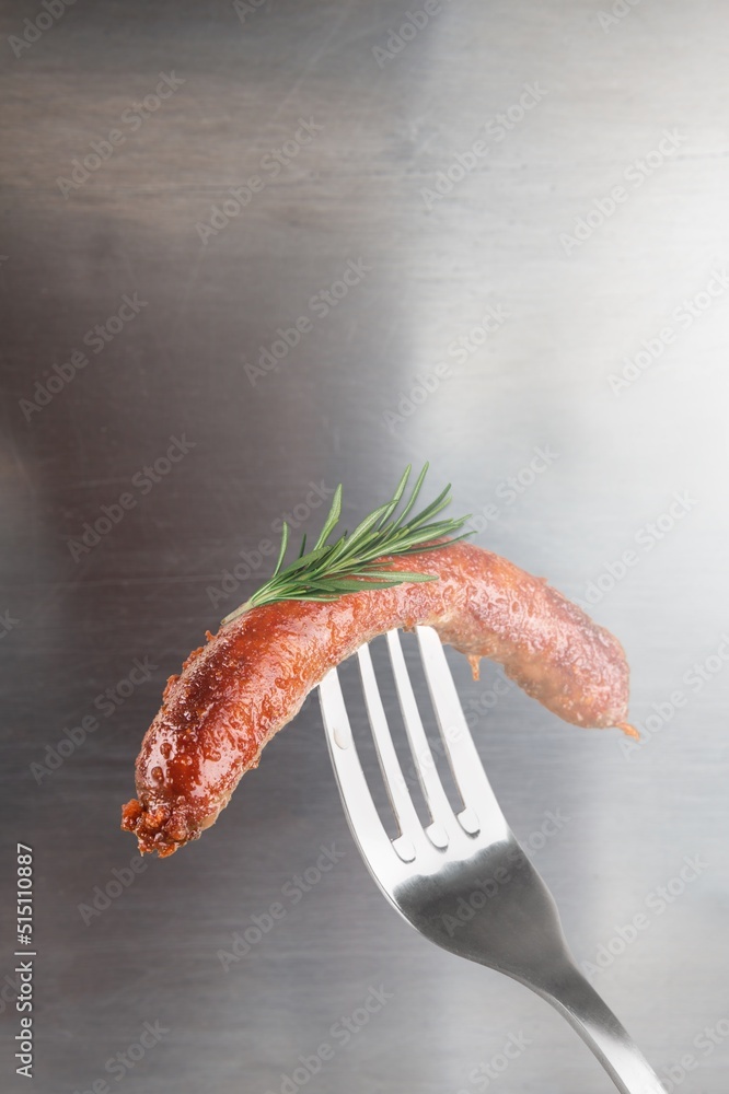 Tasty Grilled sausages with rosemary on a fork.