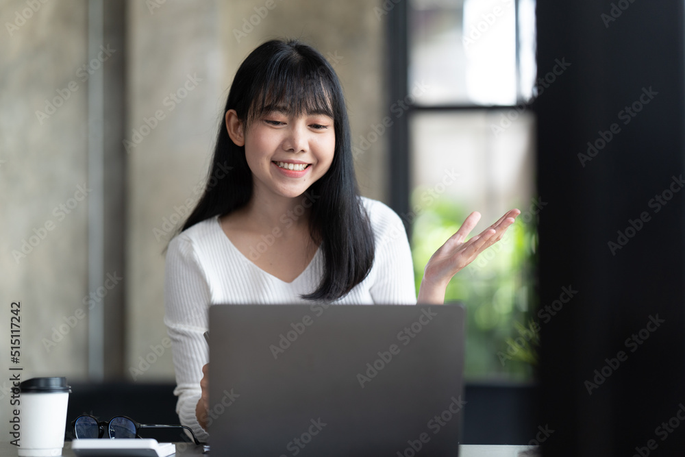 一名年轻的女学生坐在桌子旁，学习时使用电脑笔记本电脑。