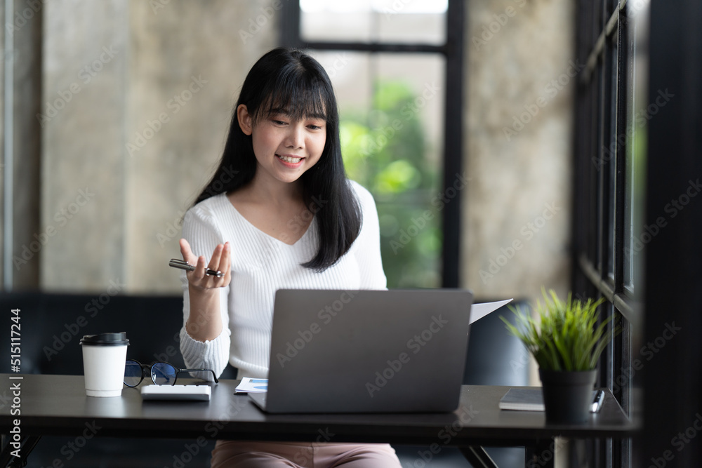 一位年轻的女学生坐在桌子旁，学习时使用电脑笔记本电脑。