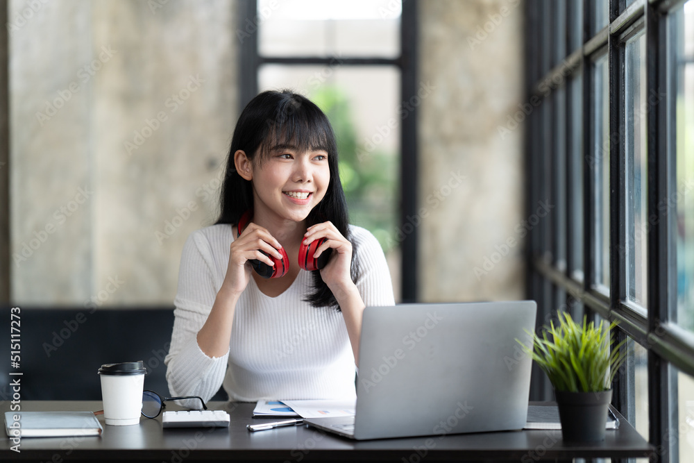 一名年轻的女学生坐在桌子旁，学习时使用电脑笔记本电脑。