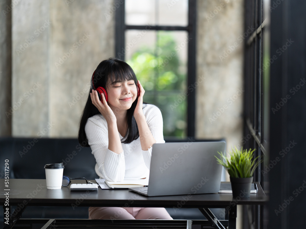 一位年轻的女学生坐在桌子旁，学习时使用电脑笔记本电脑。