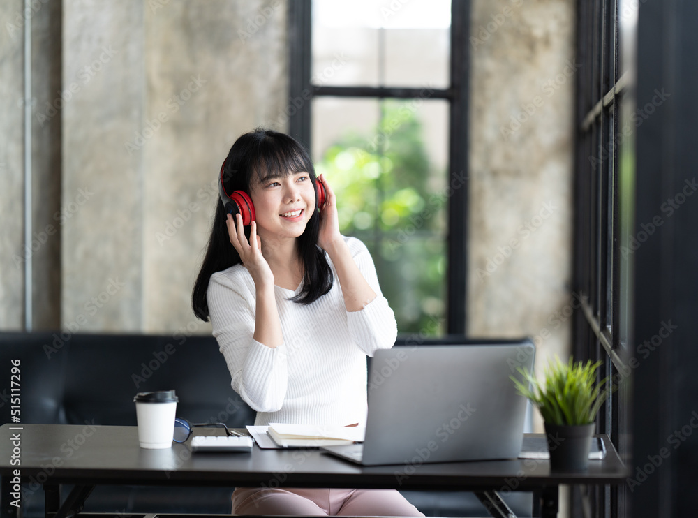 一名年轻的女学生坐在桌子旁，学习时使用电脑笔记本电脑。