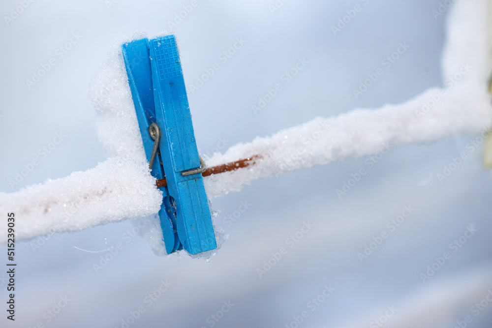 一个冰冻的蓝色木桩，上面覆盖着雪。一个旧的木制晾衣绳放在洗衣线上。