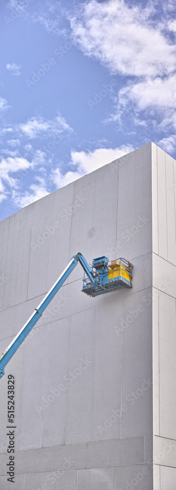 A hydraulic lift platform carrying boxes against grey wall building. Forklift or transport machinery