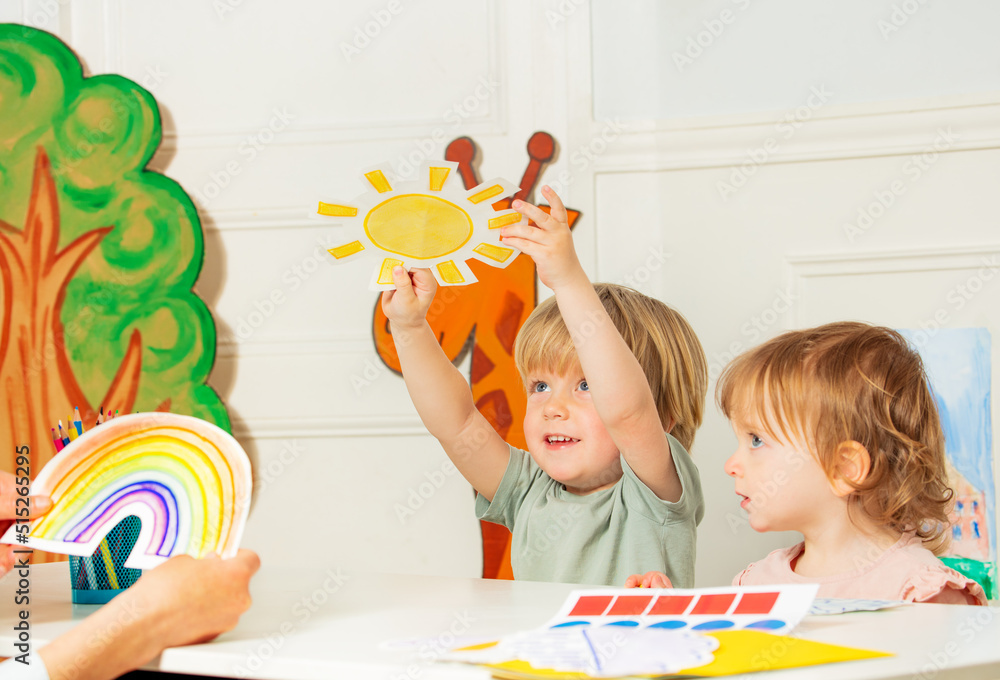 Boy in kindergarten development class show sun weather card