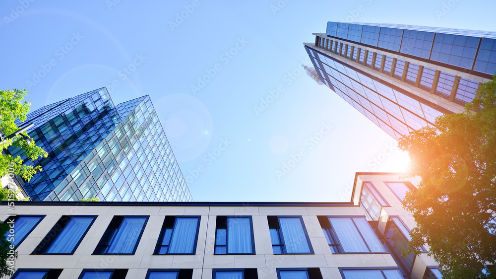 Bottom view of modern skyscraper in business district against blue sky. Looking up at business build