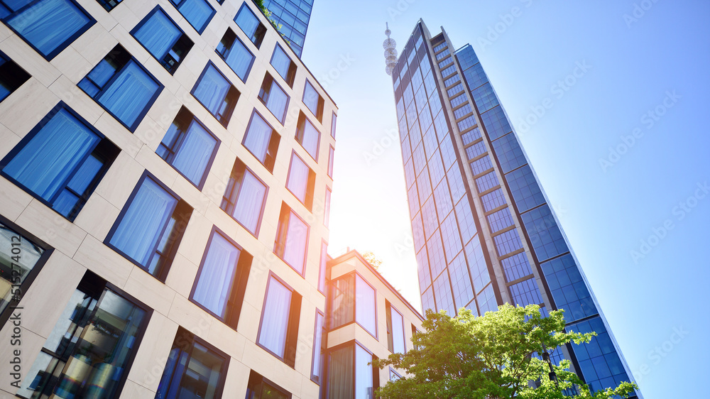 Bottom view of modern skyscraper in business district against blue sky. Looking up at business build