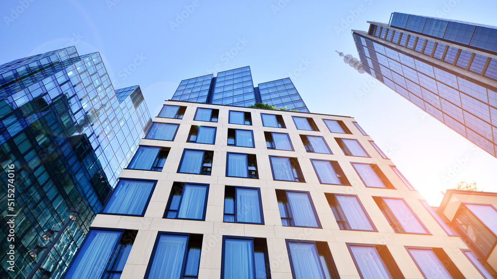 Bottom view of modern skyscraper in business district against blue sky. Looking up at business build