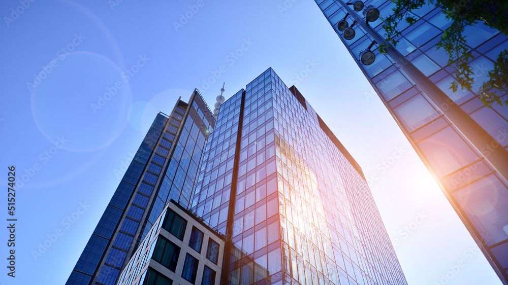 Bottom view of modern skyscraper in business district against blue sky. Looking up at business build