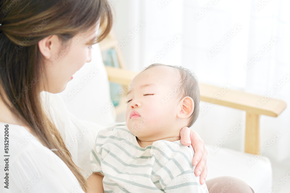 母親に抱っこされて昼寝する赤ちゃん