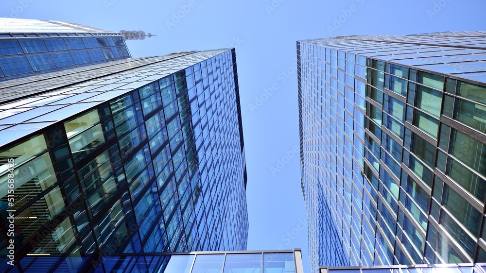 Bottom view of modern skyscraper in business district against blue sky. Looking up at business build