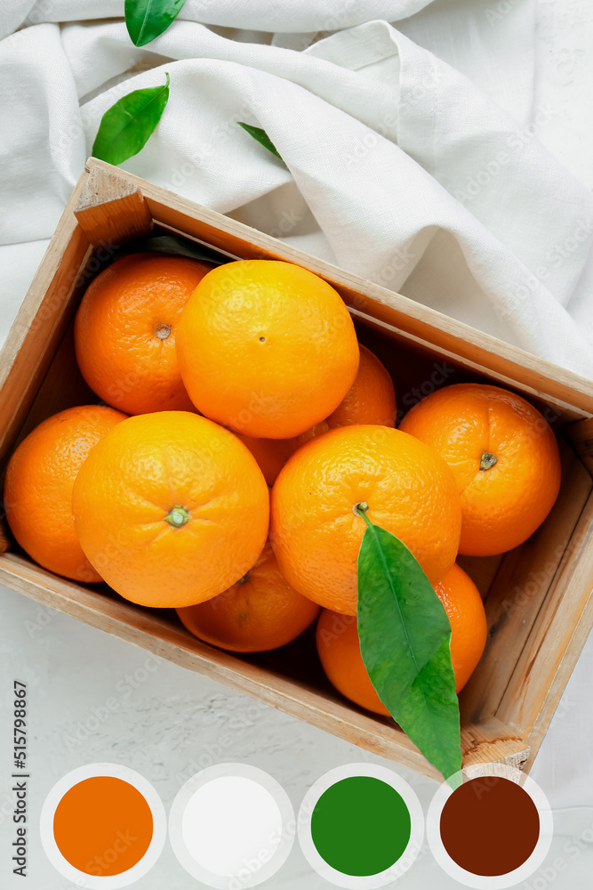 Wooden box with fresh juicy oranges on light background. Different color samples