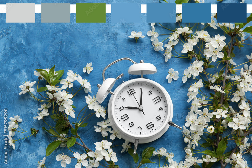 Blooming spring branches and alarm clock on blue background. Different color patterns