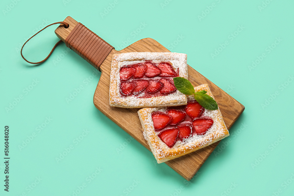 Wooden board with delicious strawberry puff pastry on color background