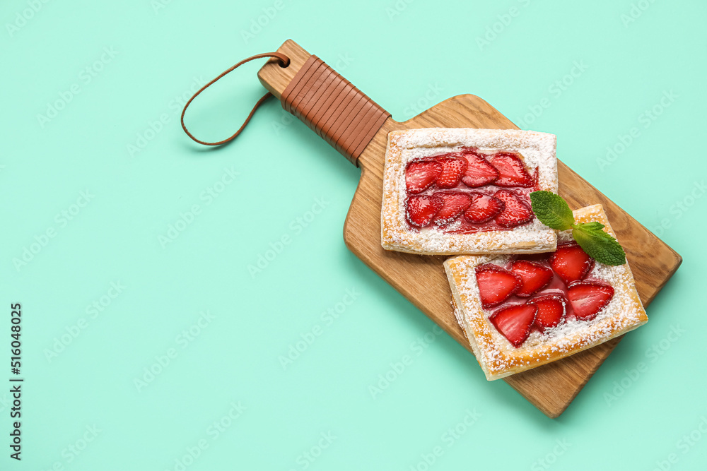 Wooden board with delicious strawberry puff pastry on color background