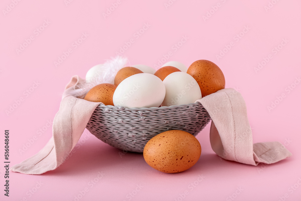 Basket with different chicken eggs ob pink background