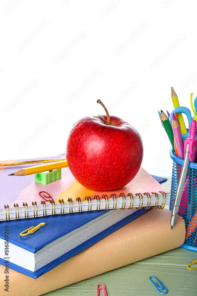 School stationery with apple and books on table against white background