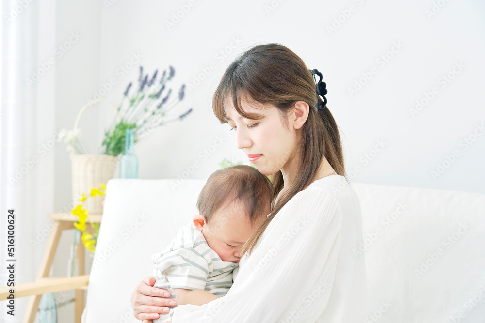 母親に抱っこされて昼寝する赤ちゃん